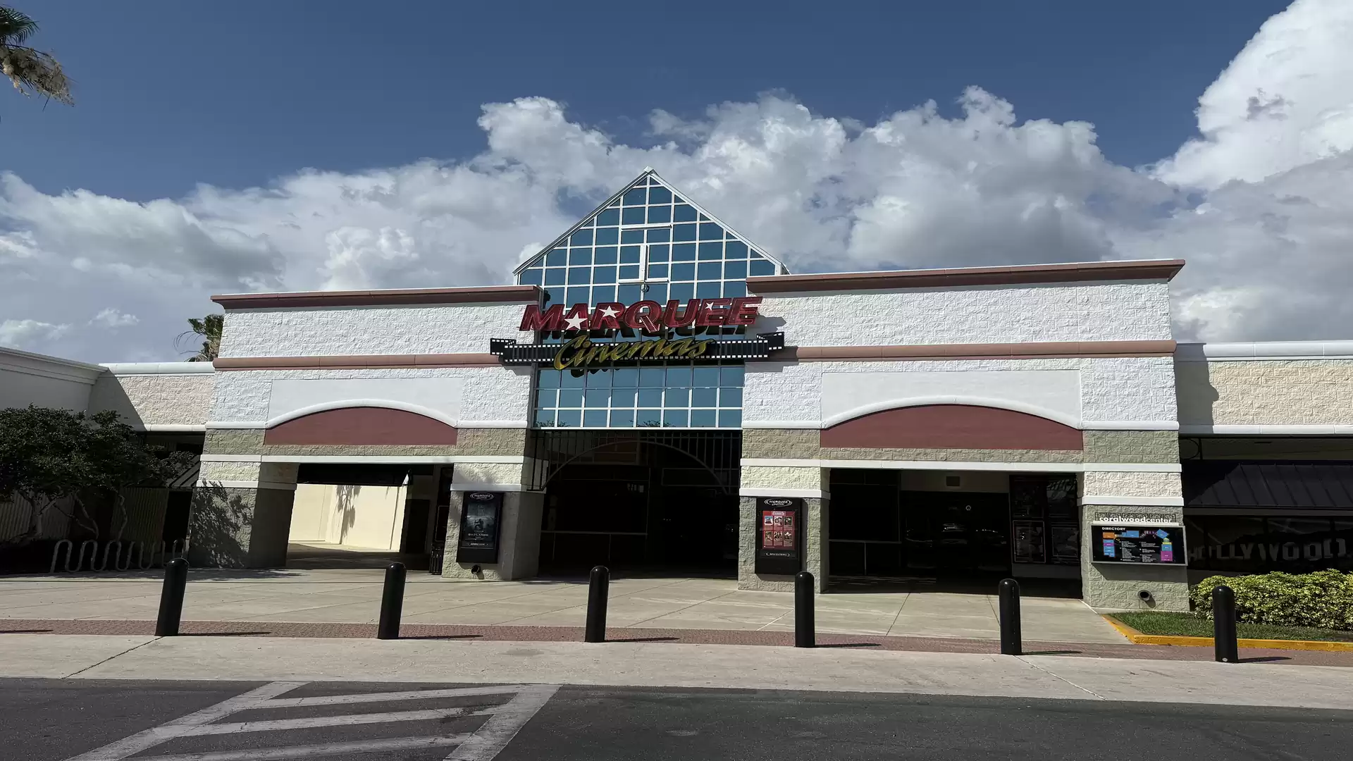 Entrance of a modern cinema during the day under a cloudy sky.