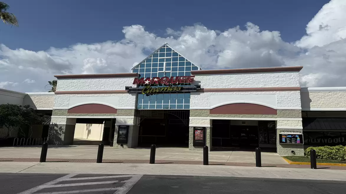 Entrance of a modern cinema during the day under a cloudy sky.