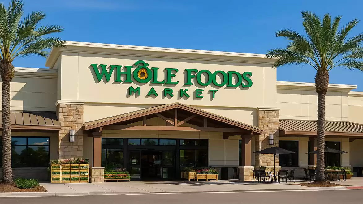 Front view of a Whole Foods Market with palm trees and clear blue sky.