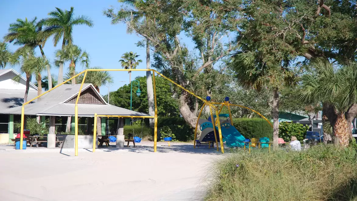 Outdoor playground with climbing frame and palm trees in the background.