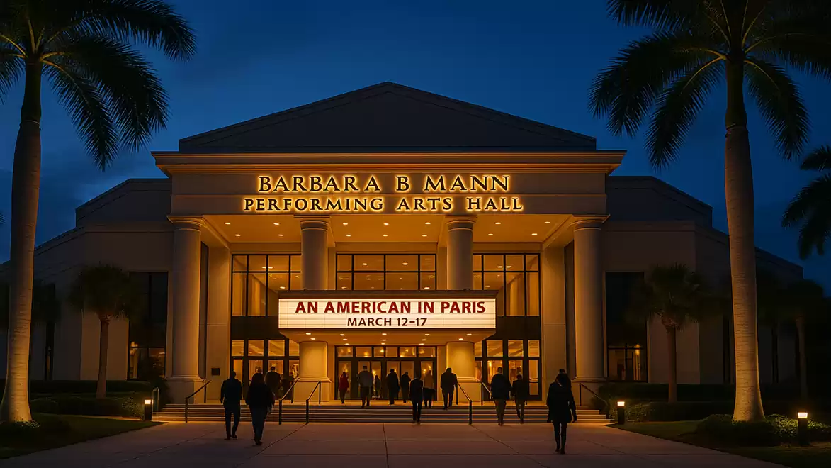 Night view of the Barbara B Mann Performing Arts Hall with a bright 'An American in Paris' sign and people entering the building.