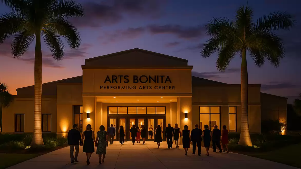 The image shows the ARTS BONITA Performing Arts Center at night, with visitors entering the doorway, surrounded by palm trees in the foreground.