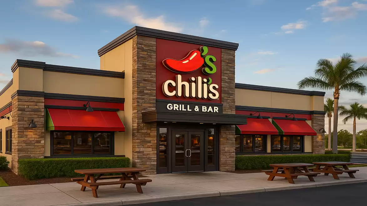 Exterior view of a Chili's Grill & Bar restaurant with its iconic red chili pepper neon sign and covered outdoor seating areas.