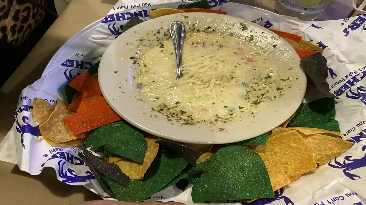 Colorful plate with nachos and cheese dip, decorated with colorful tortilla chips.