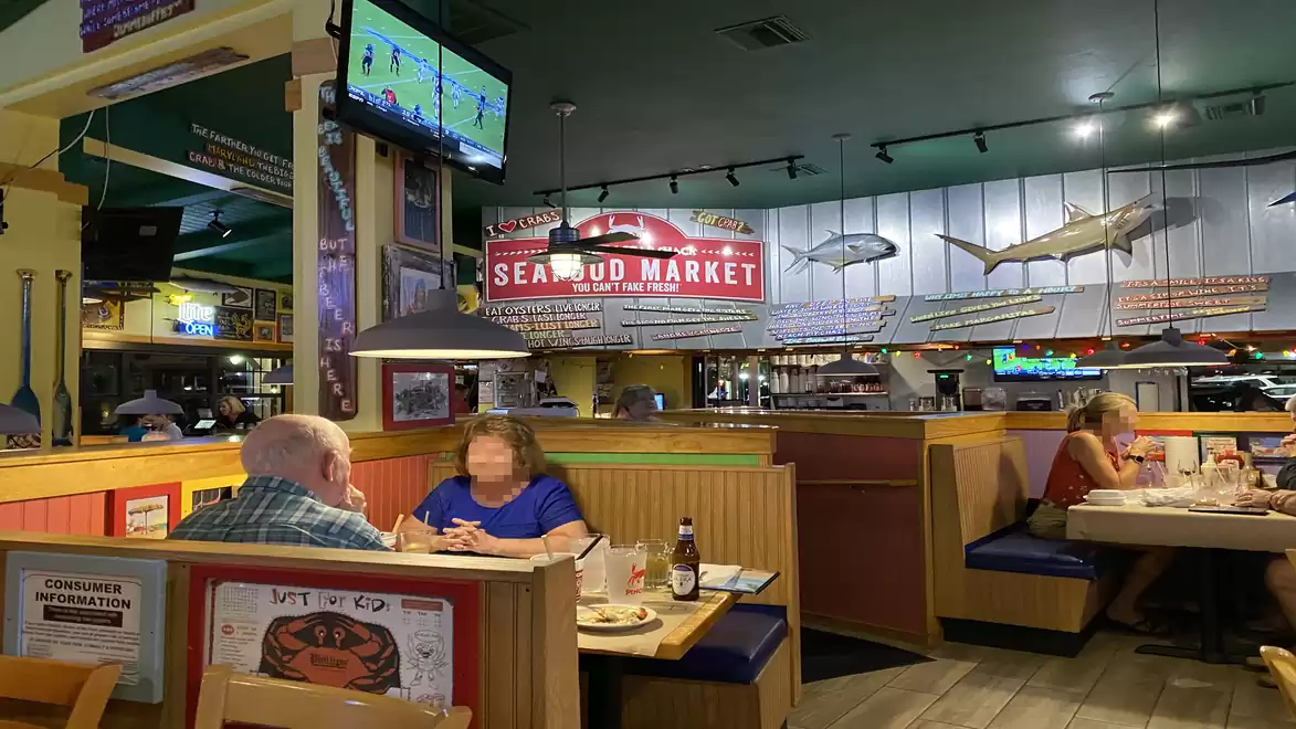 A lively restaurant with nautical decor where guests dine in cozy booths. A sign on the wall reads 'Seafood Market'.