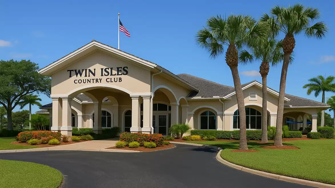 The image shows the entrance of the Twin Isles Country Club, surrounded by well-kept greenery and palm trees, with an American flag on the roof.