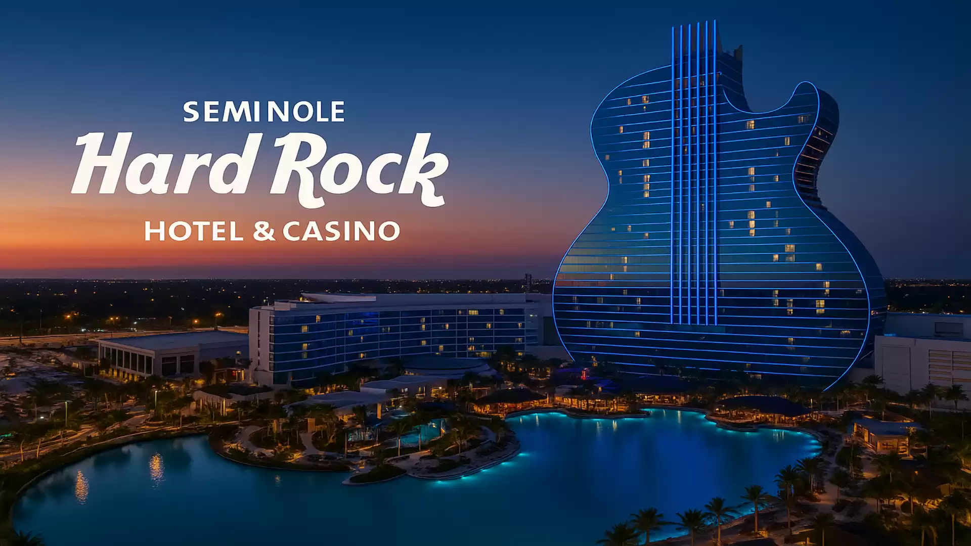 Aerial view of the Seminole Hard Rock Hotel & Casino at sunset, featuring a guitar-shaped building and glowing lights around a lake.