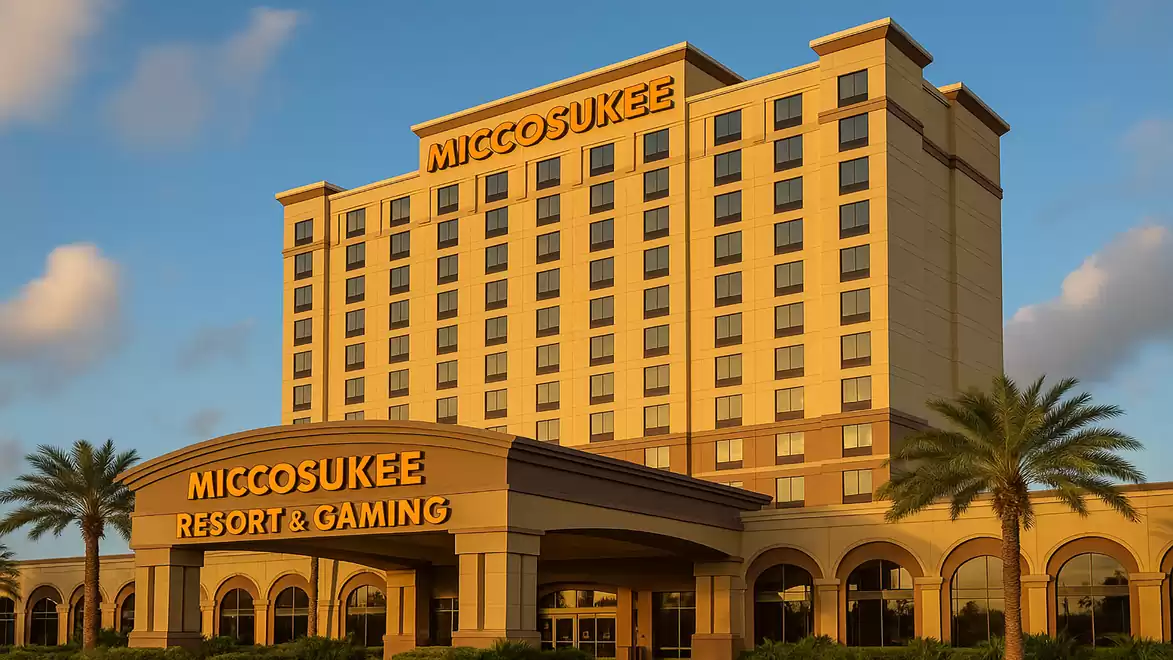 Front view of the Miccosukee Resort & Gaming with illuminated signs, surrounded by palm trees in sunset light.