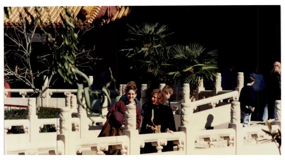 People walking in a sunny garden with Asian architectural features and exotic plants.