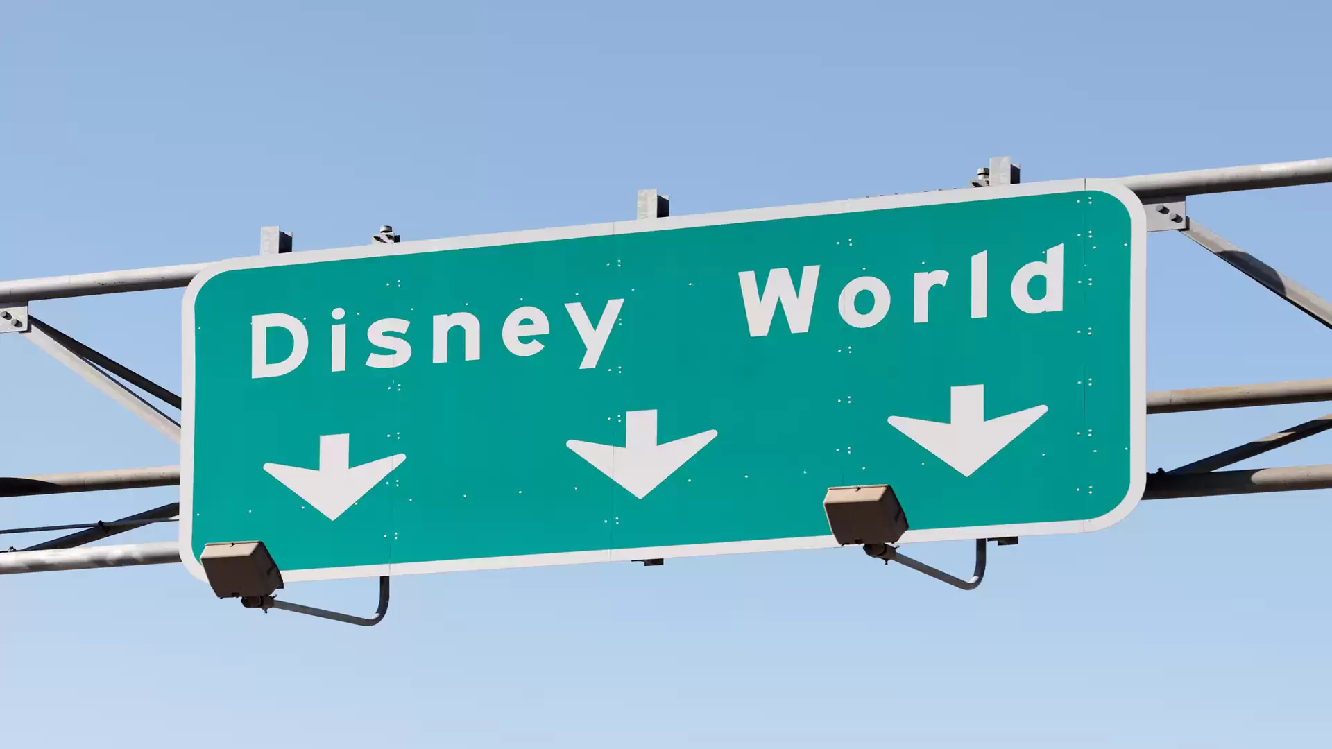 Directional sign to Disney World with three downward arrows, on a blue background.