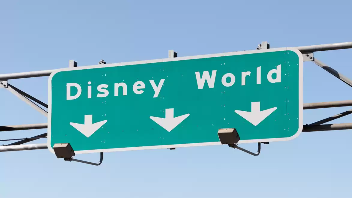 Directional sign to Disney World with three downward arrows, on a blue background.