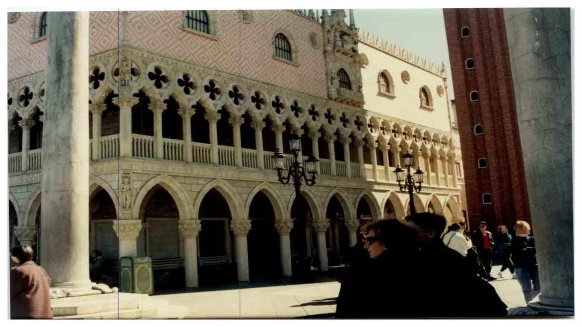 Historical architecture with Gothic arches and decorations in a sunny square.