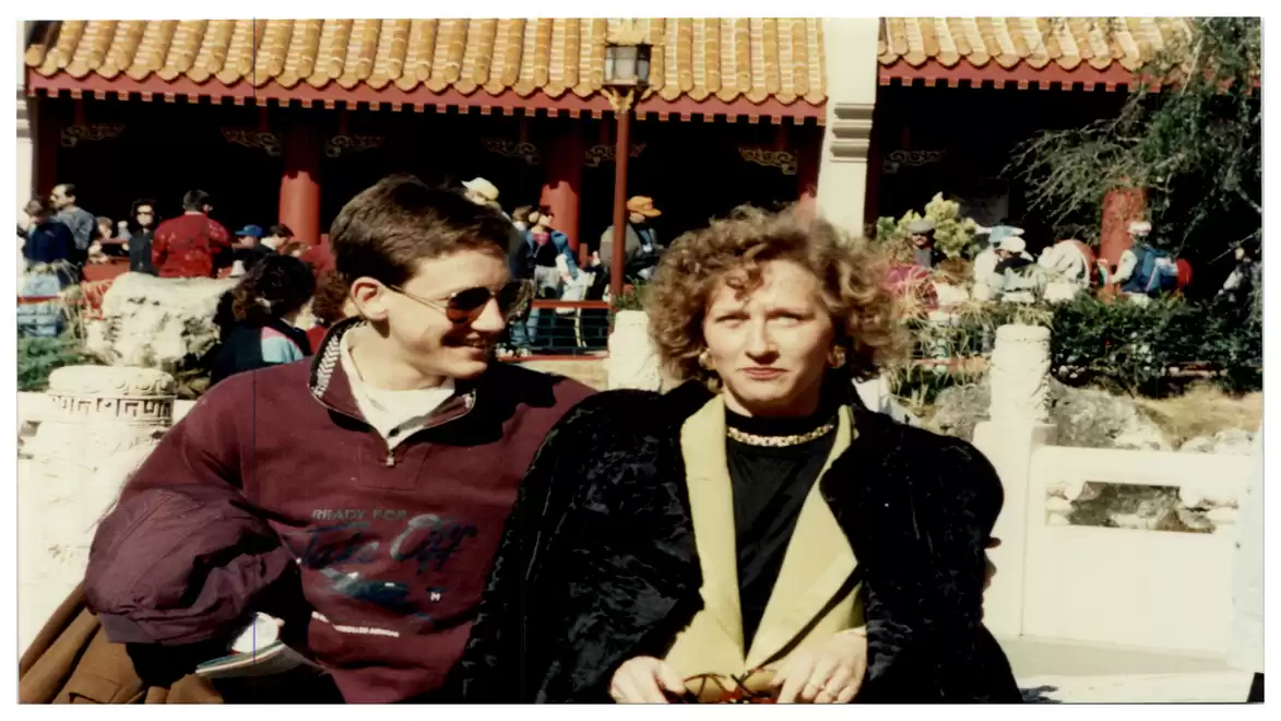 A man wearing sunglasses and a woman sitting in front of a traditional Chinese building.