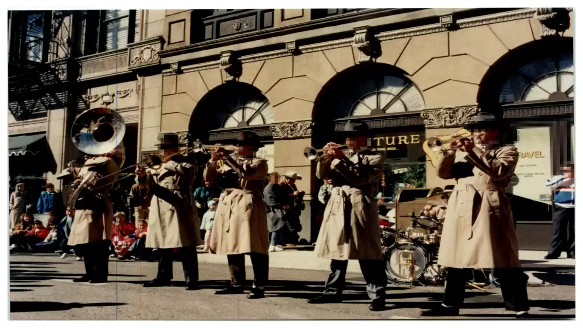Street band in trench coats playing brass instruments in front of a historic building.
