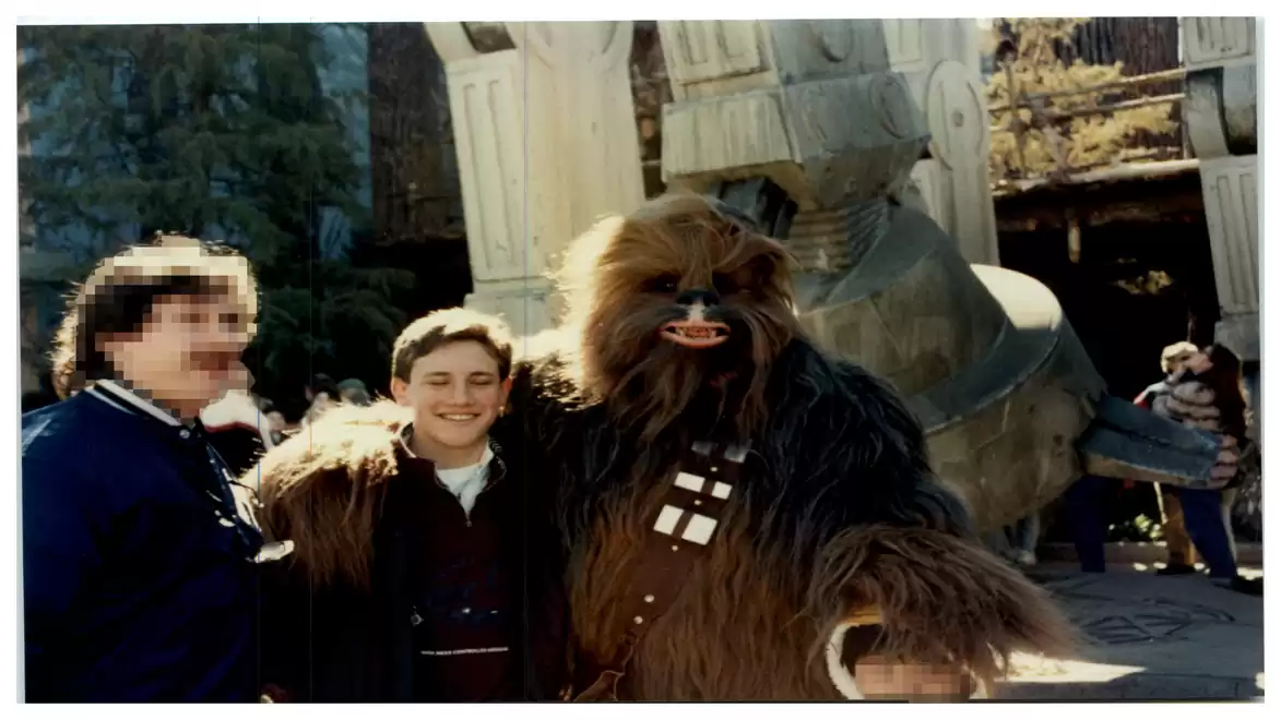 Three people in front of a Star Wars-themed background, one in a Chewbacca costume.