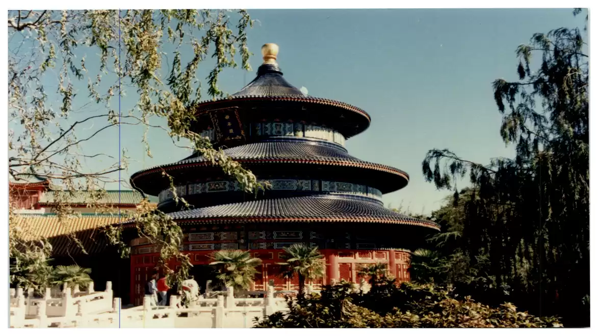 Traditional Chinese building with a pagoda roof, surrounded by trees and blue sky.