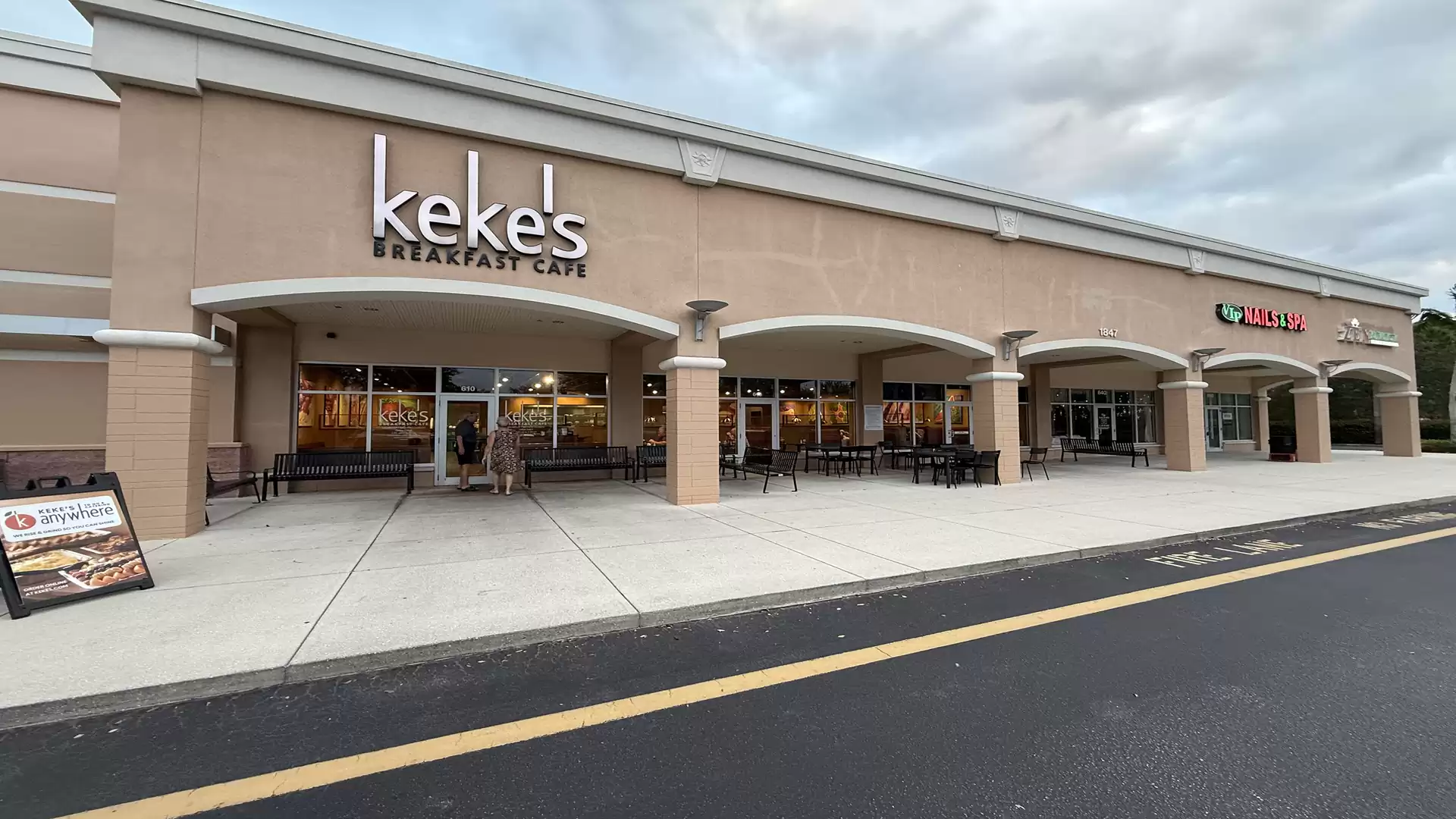Exterior view of a shopping center with restaurants, including Keke's Breakfast Cafe and Subway, under a cloudy sky.