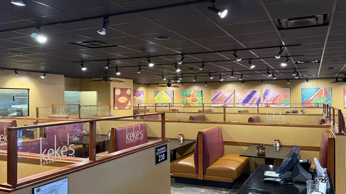 A spacious, well-lit restaurant with multiple seating booths and colorful artwork on the walls.