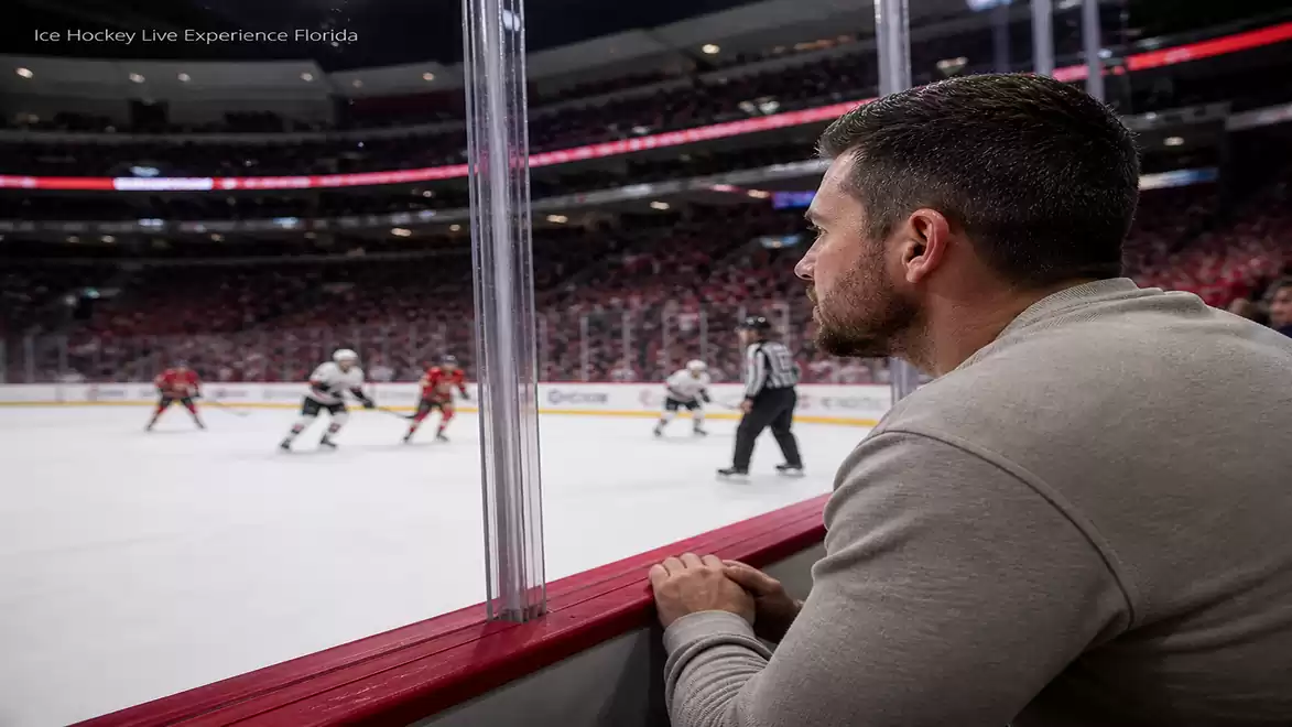 A man watches an ice hockey game in a large arena.