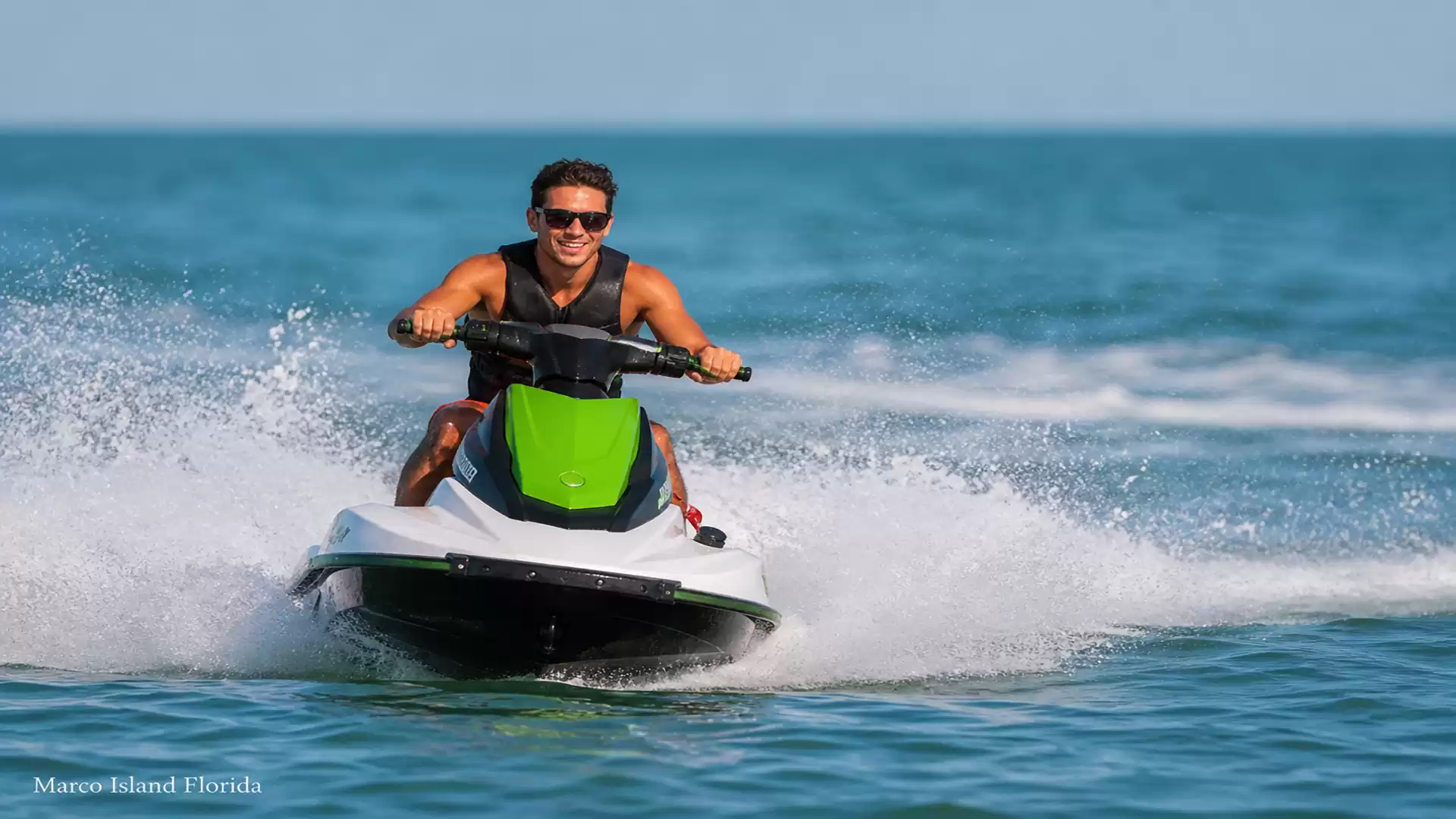 A man riding a green jet ski on the sea in sunny weather.