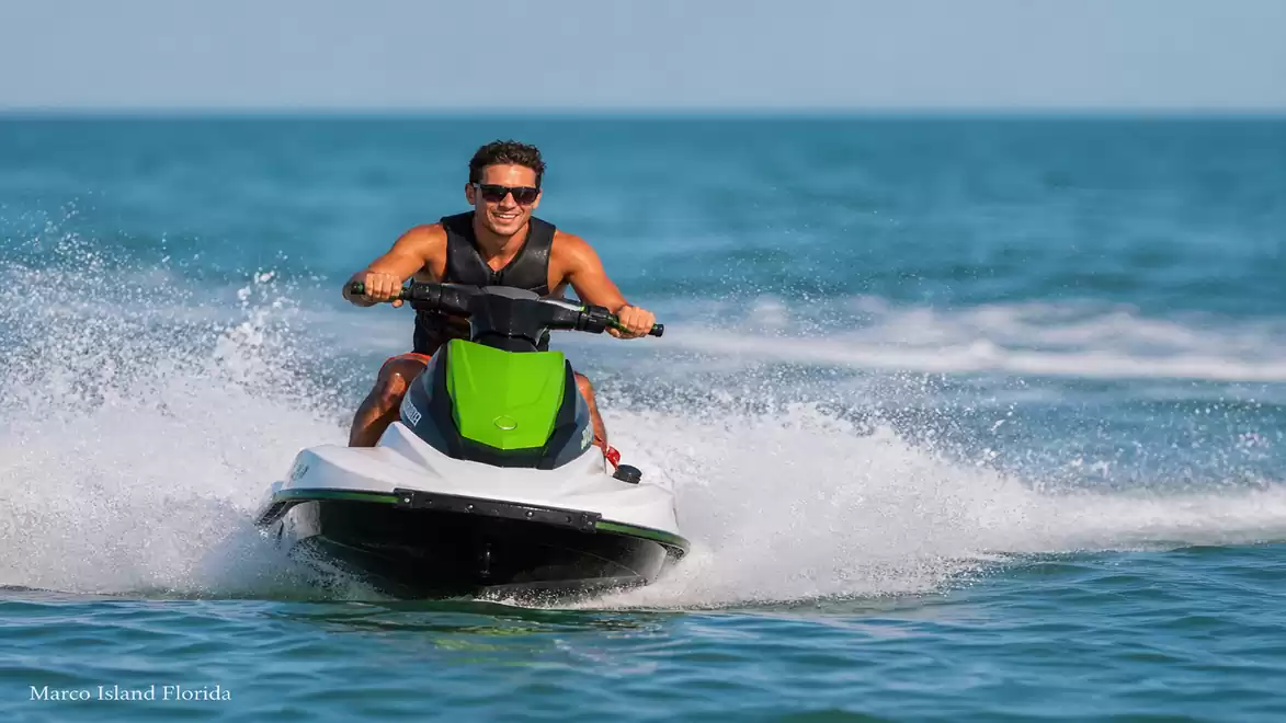 A man riding a green jet ski on the sea in sunny weather.