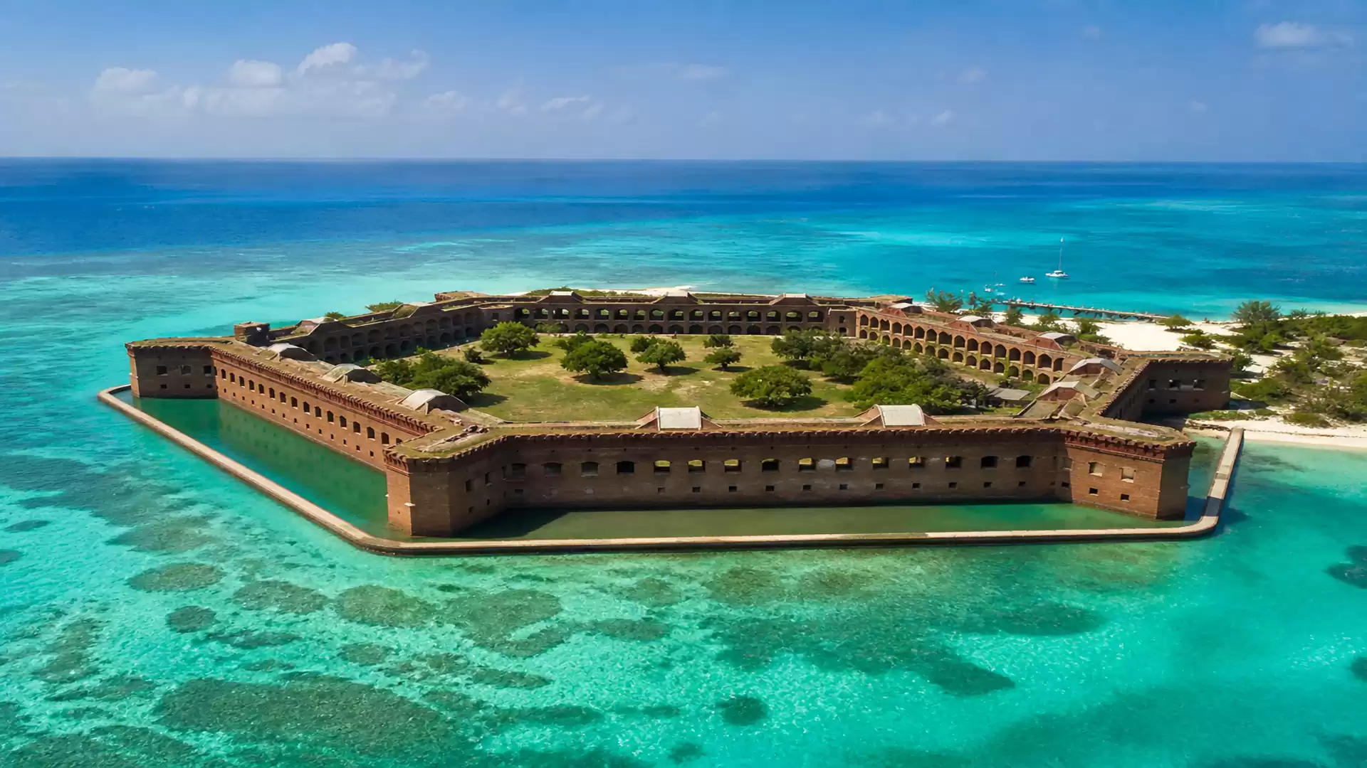 Aerial view of a historic fort on an island surrounded by turquoise blue ocean.