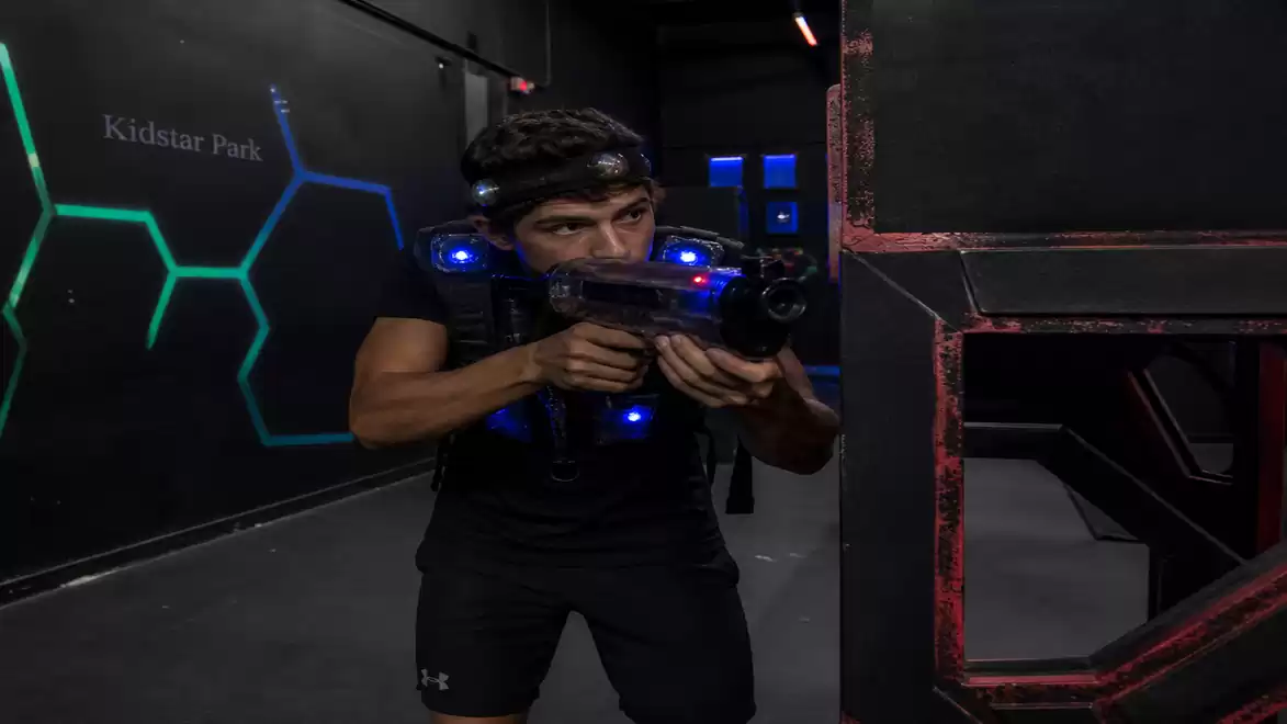 A man playing laser tag in a dark arena with lights on the wall.