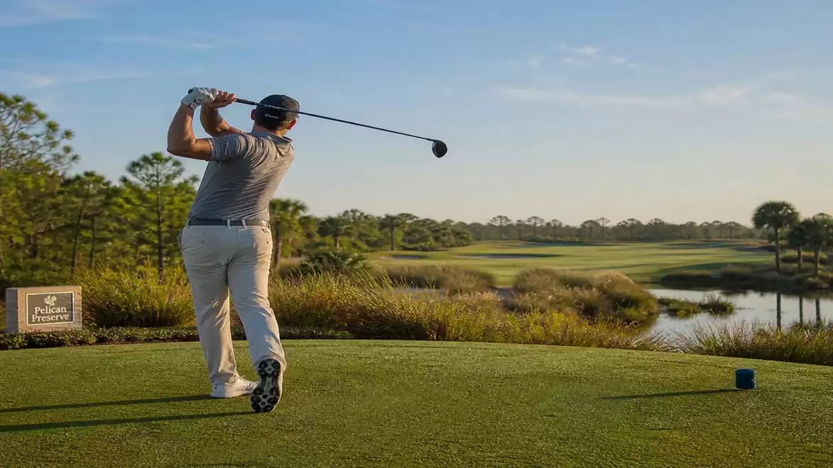 Man playing golf on a green course with a wide view of the landscape.