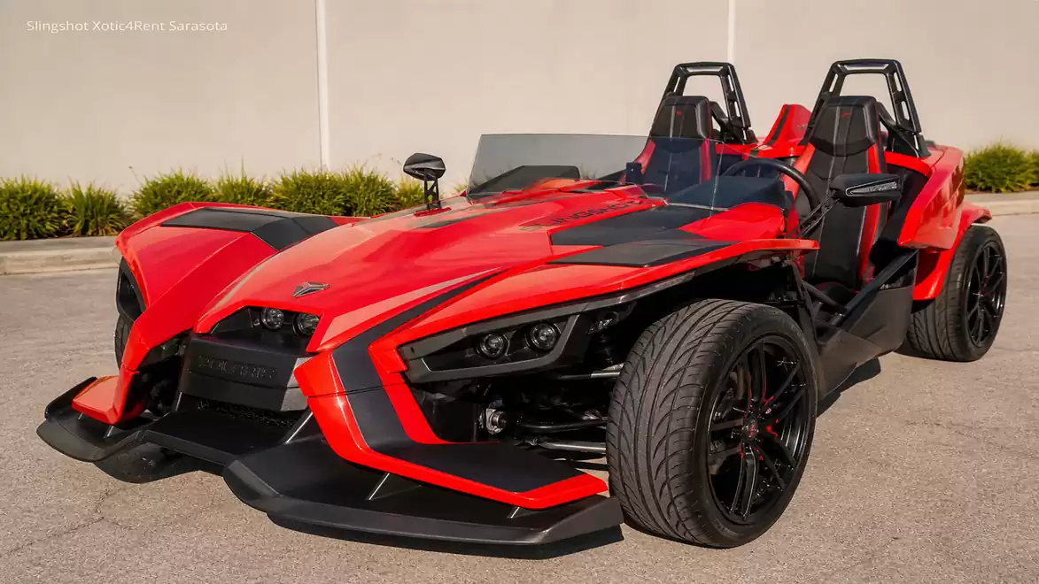 Red three-wheeled sports car in a parking lot with modern, aggressive lines.