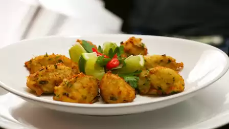 A plate of fried potato croquettes with fresh lime garnish, decorated with red chili peppers.
