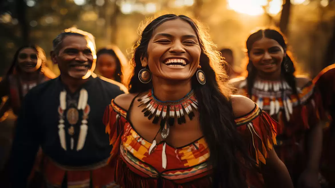 A group of smiling people in traditional outfits, surrounded by soft sunlight in a forest.