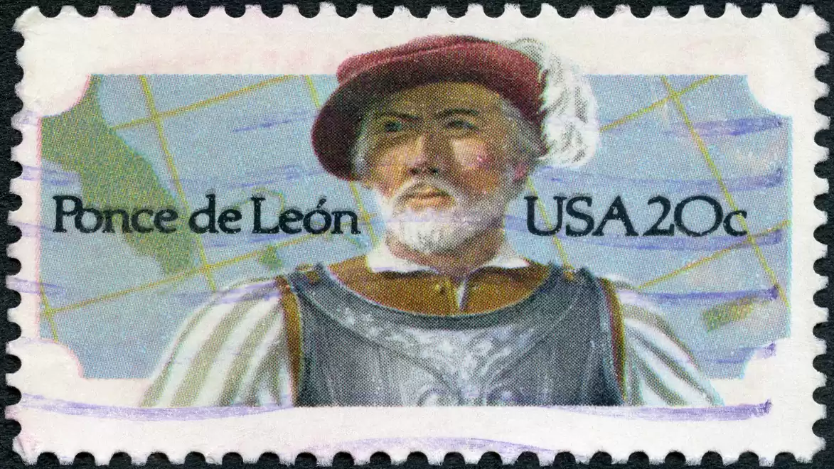 Stamp featuring a man in historical clothing and a hat. Beside him are the words 'Ponce de León' and 'USA 20c'. A map is in the background.