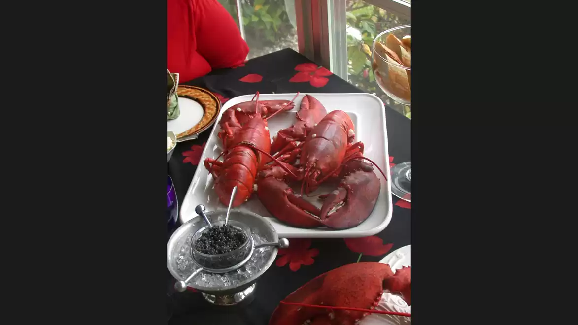 A table with fresh lobster on a plate and utensils ready for dining.