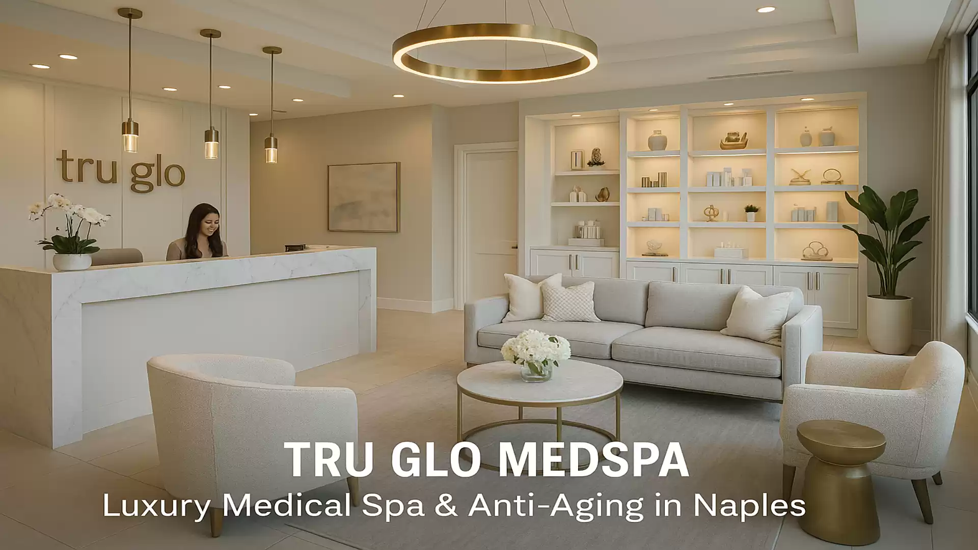 Interior view of a luxury medical spa with a reception area, seating, and decorative shelves. A person is standing behind the reception.