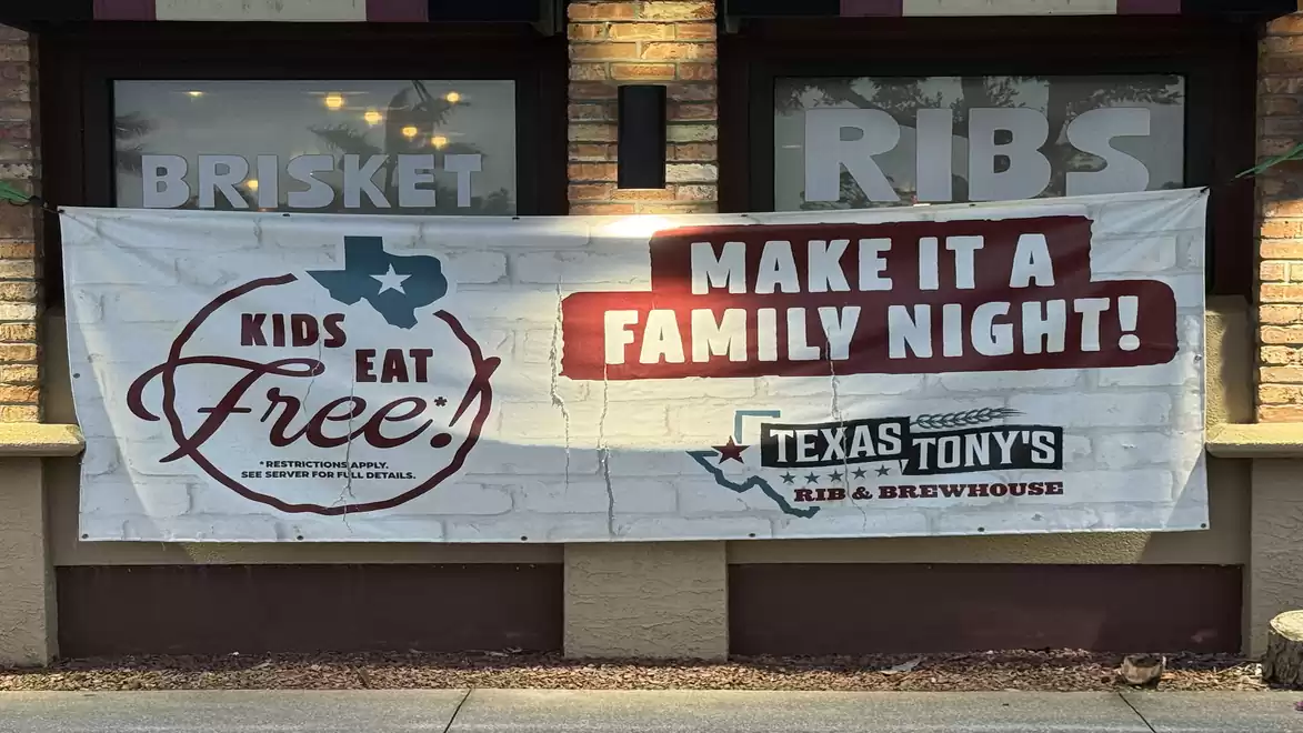 Banner in front of a restaurant with the text 'Kids eat free' and 'Make it a family night' at Texas Tony's Rib & Brewhouse.
