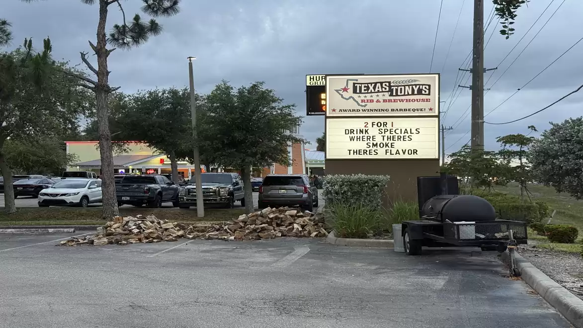 Image of a barbecue restaurant advertisement with a large sign showing specials and the phrase 'Where There's Smoke, There's Flavor'; a smoker is seen in the foreground.