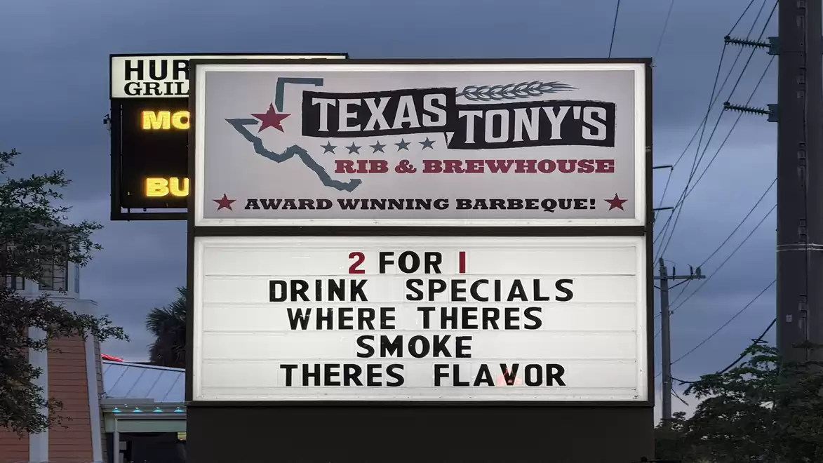 An advertising sign for Texas Tony's Rib & Brewhouse featuring a 2-for-1 drink special and the phrase 'Where there's smoke, there's flavor'.
