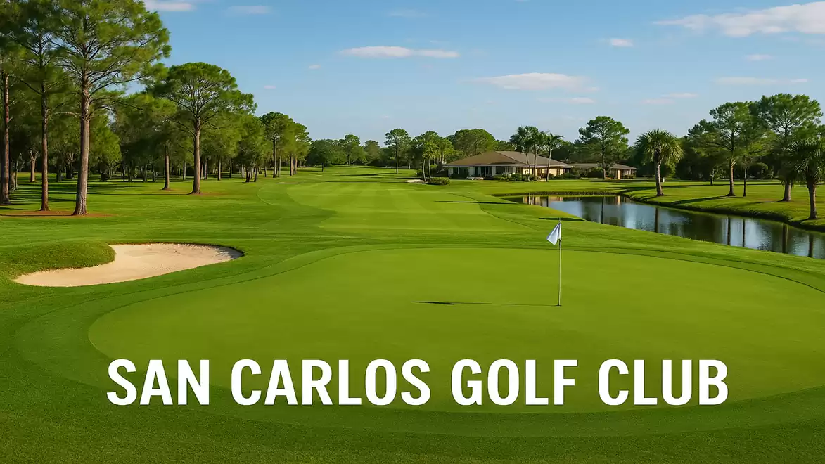 Golf course with green lawns, sand bunker, trees, and water hazard, clubhouse in the background.
