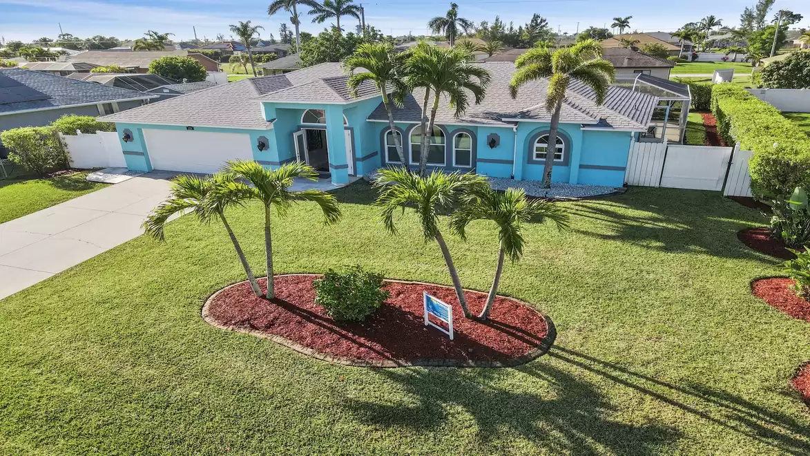 Aerial view of a modern, turquoise single-family home - Villa Orange Cove - with a palm garden.