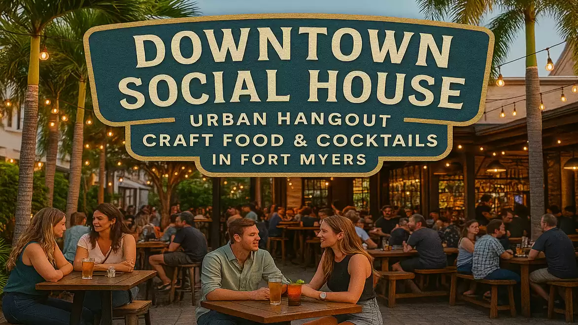 People sitting and enjoying drinks and food in the outdoor area of Downtown Social House in Fort Myers with a large promotional sign in the background.