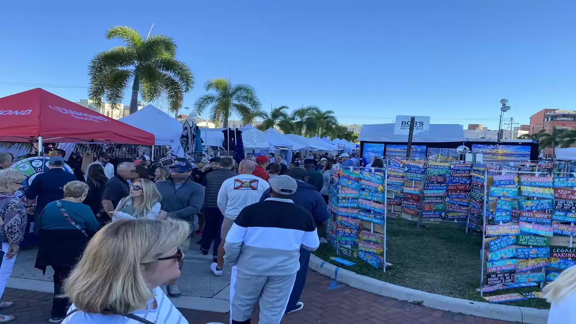 Outdoor market with many people and stalls under a blue sky.