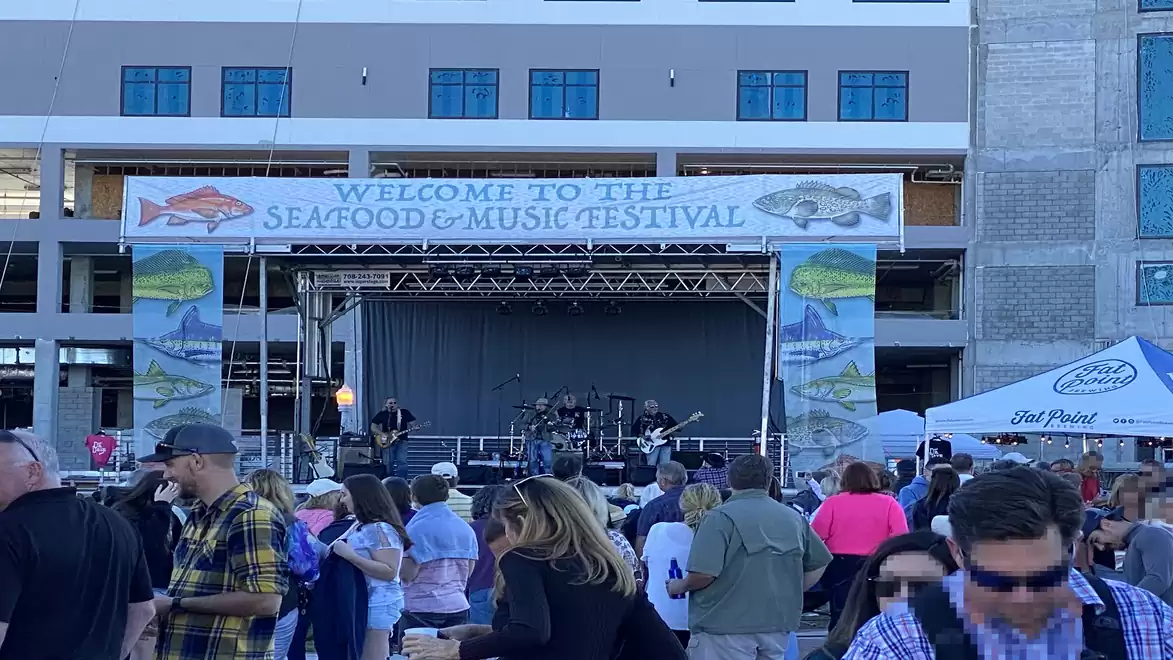 Crowd at a seafood and music festival in front of a stage with a live band.