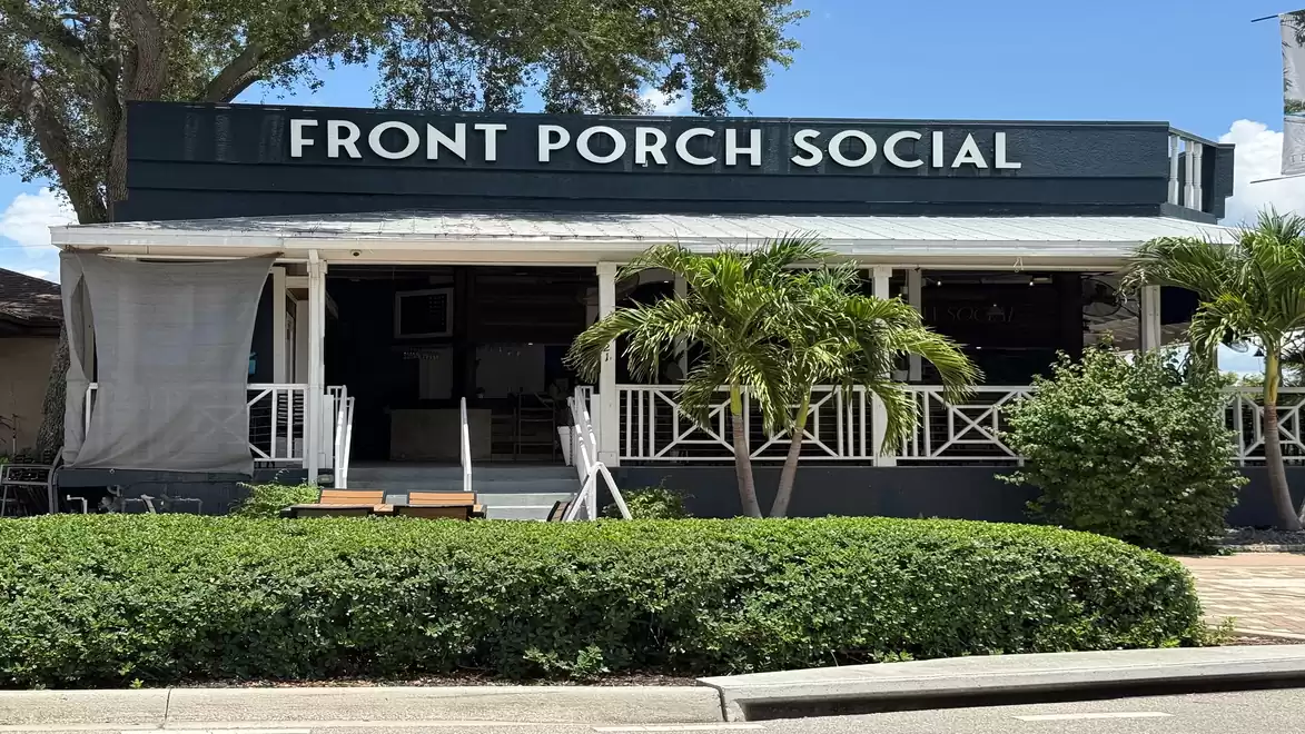 Exterior view of a café named Front Porch Social with a porch and palm trees in the foreground.
