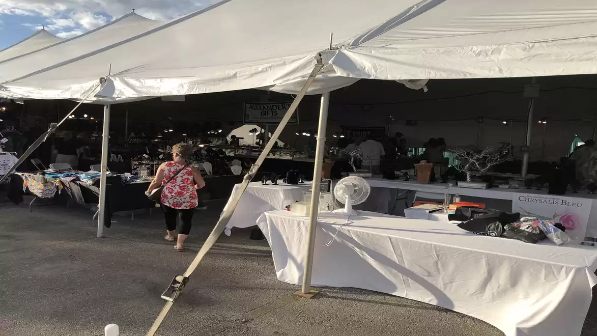 A large white market stall with various products and a person walking by.