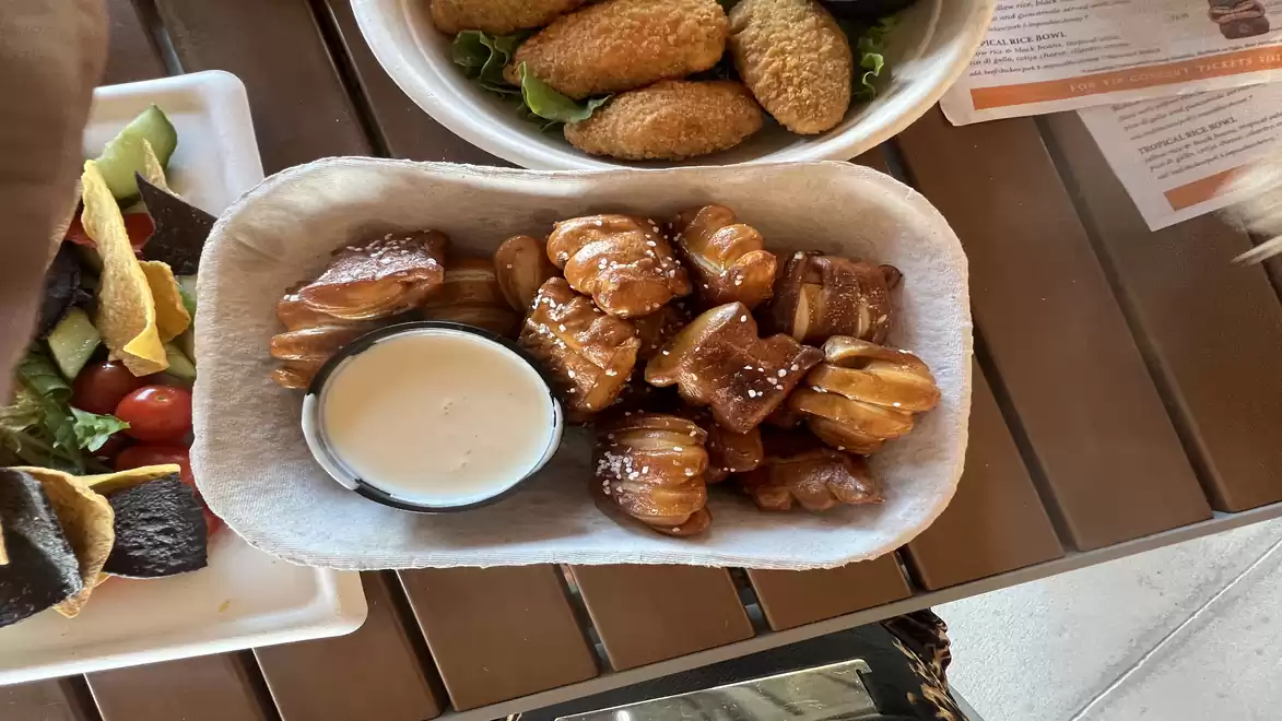 A table with various snacks and a dip, including pretzels and croquettes.