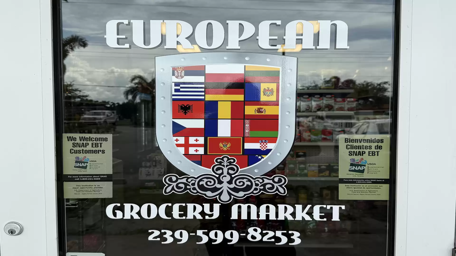 Entrance of a European grocery market featuring a sign with various European national flags.
