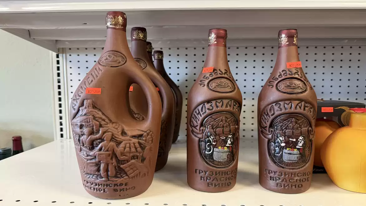 Image of Georgian wine bottles made of clay ceramic with artistic reliefs in a store.