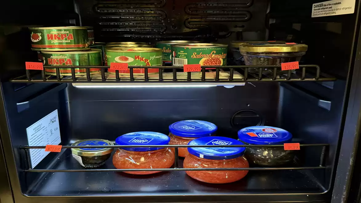 Open fridge displaying various canned and jarred foods arranged on shelves.