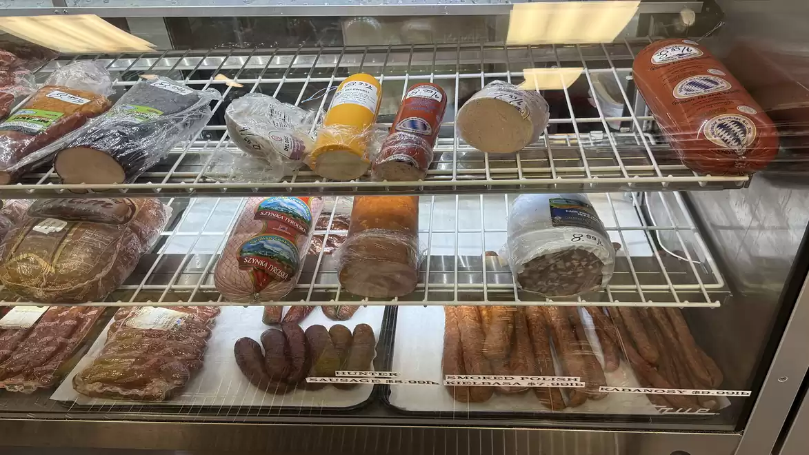 A refrigerated display case with various types of sausages, including salami, cold cuts, and sausages.