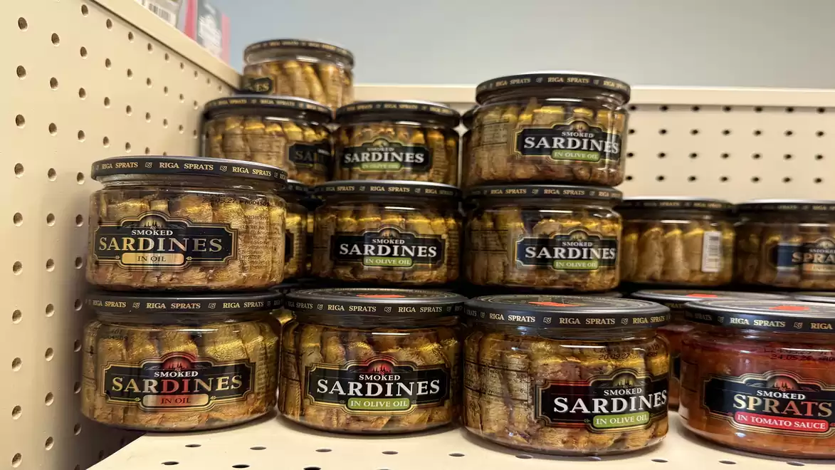 A shelf filled with jars containing smoked sardines and sprats.